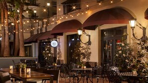 An outdoor dining area with tables and chairs, string lights, and potted plants.
