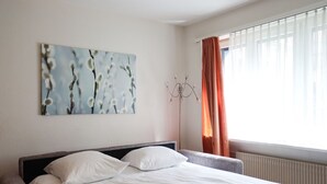 Een hotelkamer met een bed, een schilderij aan de muur en een raam met gordijnen.