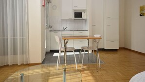 A compact kitchen with white cabinets, a microwave, a sink, and a dining area with two chairs. - Very central & bright studio (Vineyard 51) (Zürich)
