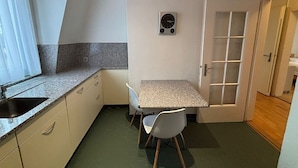 Et lille køkken med en bordplade i granit, en vask, et ur og et spiseområde med to stole.