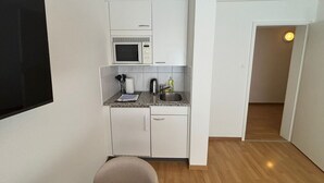 A compact kitchen with white cabinets, a microwave, a sink, and a small countertop.