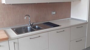 A modern kitchen with white cabinetry, a stainless steel sink, and a tiled backsplash. - 5 minutes walk from the beach - New Apartment with 2 bedrooms in Italy (Giulianova)