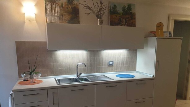 A modern kitchen with a double sink, white cabinets, and a tiled backsplash. - 5 minutes walk from the beach - New Apartment with 2 bedrooms in Italy (Giulianova)