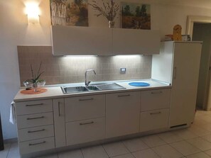 A modern kitchen with a double sink, white cabinets, and a tiled backsplash. - 5 minutes walk from the beach - New Apartment with 2 bedrooms in Italy (Giulianova)