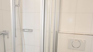 A modern bathroom with a glass-enclosed shower, a white toilet, and a sink. - Cozy studio near main station (Color 2) (Zürich)