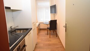 A compact kitchen with a sink, stove, and dining area with a table and chairs. - Cozy studio near main station (Color 2) (Zürich)