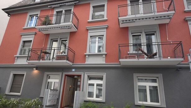 A multi-story building with balconies, a ground entrance, and a visible door. - Cozy studio near main station (Color 2) (Zürich)