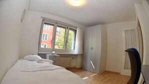 Een slaapkamer met een bed, een bureau en een kledingkast.