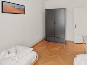 Una camera da letto con un letto, un armadio, una porta e un quadro appeso al muro.