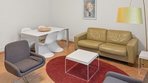 A modern living room with a grey armchair, a beige sofa, a white coffee table, and a red rug. - 2BR near lake (Stardust 11) (Zürich)
