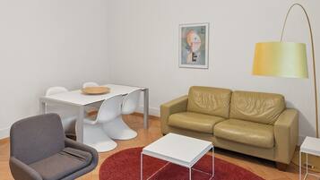 A modern living room with a grey armchair, a beige sofa, a white coffee table, and a red rug.