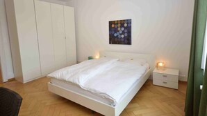 Une chambre à coucher comprenant un lit, des tables de chevet, une armoire et une œuvre d’art murale.
