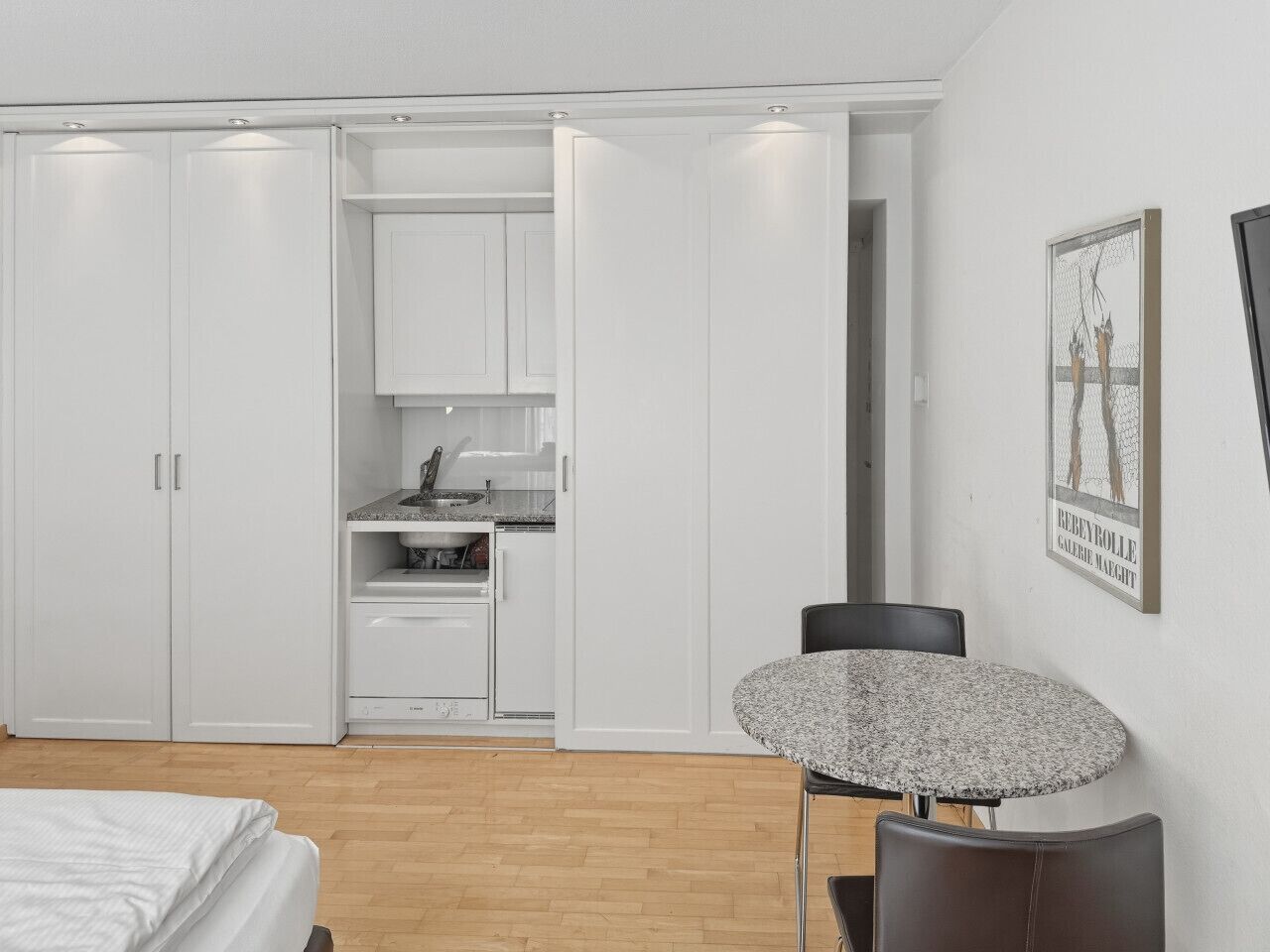 Ein Schlafzimmer mit Bett, Esstisch, Küchenzeile und Kleiderschrank.