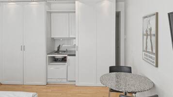 Ein Schlafzimmer mit Bett, Esstisch, Küchenzeile und Kleiderschrank.