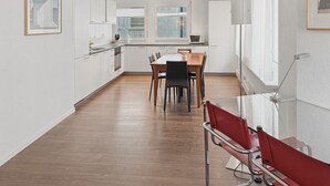 Eine moderne Küche mit weißen Schränken, einem Holztisch und einem roten Stuhl.