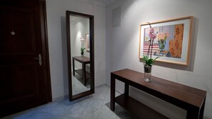 Ein Flur mit einer Holztür, einem Spiegel, einer Bank und einem gerahmten Gemälde an der Wand.