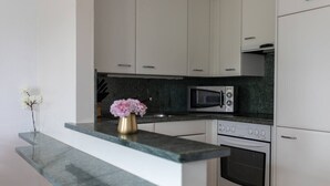 Eine moderne Küche mit weißen Schränken, einer Granit-Arbeitsplatte, einer Mikrowelle und einem Backofen.
