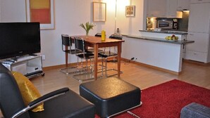 Ein kompakter Wohnraum mit Essbereich, Küchenzeile und Flachbildfernseher.