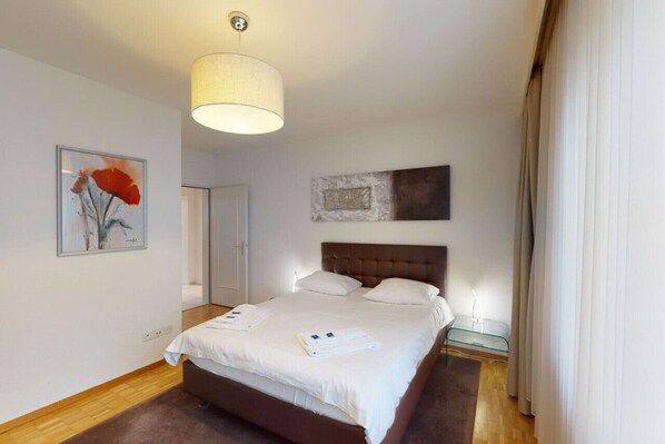 A hotel room with a large bed, a headboard, a bedside table, and a painting on the wall. - Executive 1BR flat, city center (Hammer 1) (Zürich)
