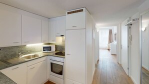 Una cocina moderna con armarios blancos, un microondas, un lavamanos y un horno.
