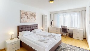 A modern hotel room with a large bed, bedside tables, a desk, and a chair.