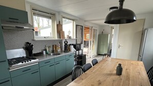 Une cuisine moderne avec des meubles de couleur turquoise, une table à manger en bois et un luminaire suspendu noir.