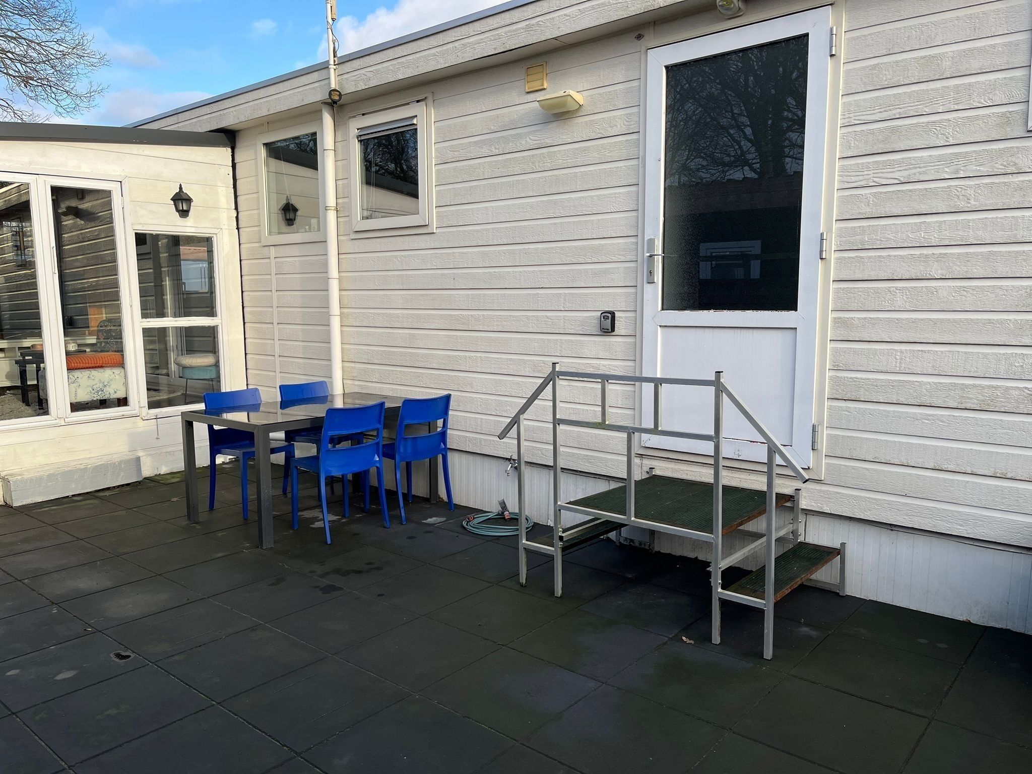 A patio with a table and chairs, a small play structure, and a door to a house.