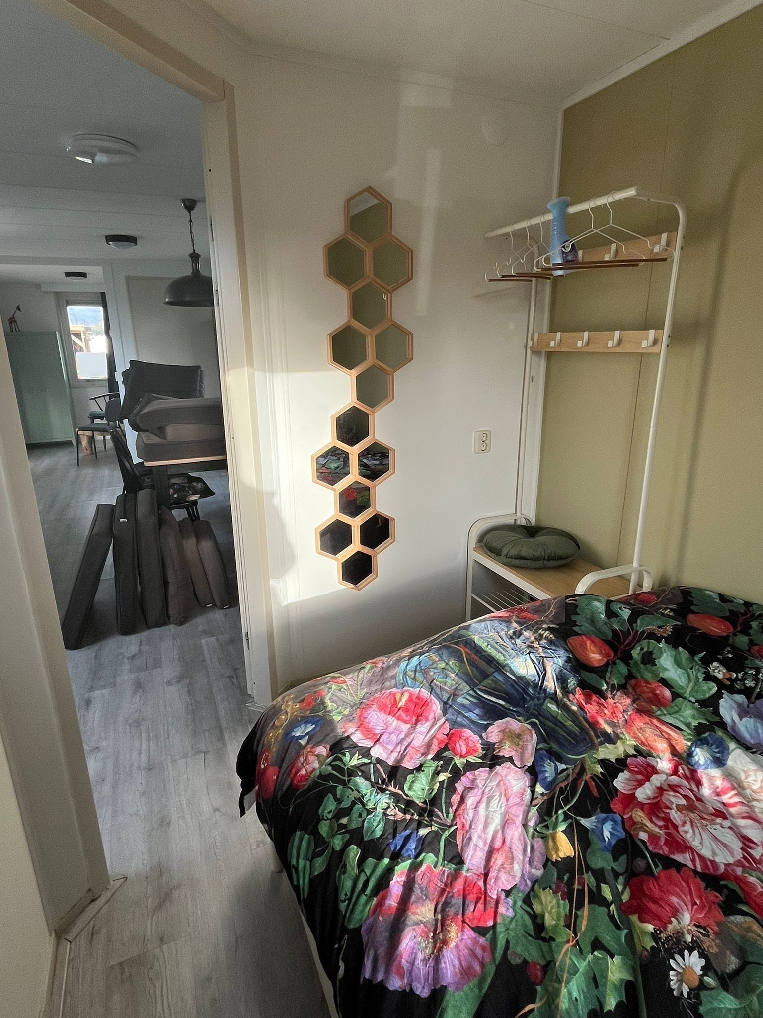 Un dormitorio con colcha estampada, literas, un espejo montado en la pared y un perchero.