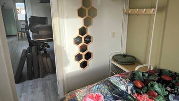 Un dormitorio con colcha estampada, literas, un espejo montado en la pared y un perchero.