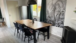 Un coin repas avec une table en bois et des chaises noires, un petit réfrigérateur et un radiateur noir.
