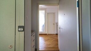 A hallway with a wooden floor leading to a room with a white door.