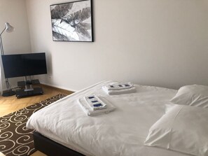 A hotel room with a bed, a desk with a lamp, and a framed picture on the wall. - Bright studio in the city center (Greenyard 1) (Zürich)