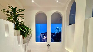 A staircase with a view of a cityscape at dusk through arched windows. - Le Huynh Mui Ne Hotel (Mui Ne)