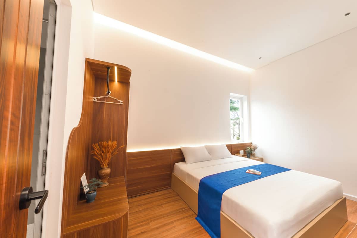 Un dormitorio moderno con cama, mesitas de noche, un armario de madera y una televisión.