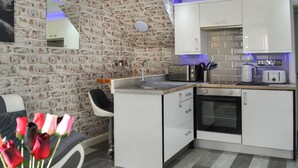 A compact kitchen with a brick wall, white cabinets, a small island, and a toaster.