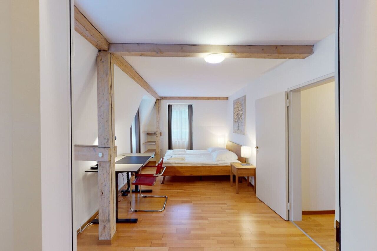 A bedroom with a bed, a desk, and a chair.
