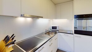 A modern kitchen with white cabinets, a black countertop, a built-in microwave, and a stainless steel sink. - Penthouse flat in the city center/near lake (SF18) (Zürich)