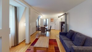 A modern living room with a sofa, a dining table, and chairs. There is a kitchen area with a refrigerator and cabinets. - Penthouse flat in the city center/near lake (SF18) (Zürich)