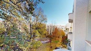 A view from a balcony overlooking a courtyard with trees and a circular path.