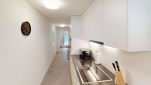 Una cucina moderna con piano cottura integrato, una sveglia al muro e un portachiodi.