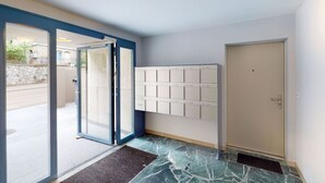 Ingresso di un hotel con porta in vetro, una cassetta postale a parete e una porta con pomello.