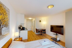 Ein Hotelzimmer mit Bett, Schreibtisch mit Stuhl, Fernseher und einem Gemälde an der Wand.