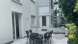 A patio with a table and chairs, a sliding glass door, and a concrete floor.