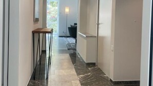 A hallway with a marble floor, a wooden table, and a lamp.