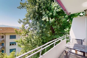 Enjoy the serene view of the surrounding tree and neighboring building from this balcony.