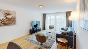 Een moderne woonkamer met een bank, fauteuil en een televisie op een dressoir.