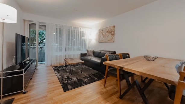 A modern living room with a sofa, a dining table, and a TV. - Fantastic 2BR in the city center (Sky7) (Zürich)