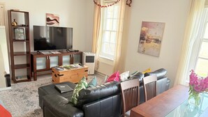 A living room with a sofa, a coffee table, a TV, and a dining table.