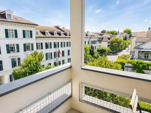 Un balcón con vista a una zona residencial, con edificios de varios pisos y persianas verdes.