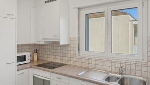 A kitchen with white cabinets, a microwave, a dishwasher, a sink, and a window with a view.